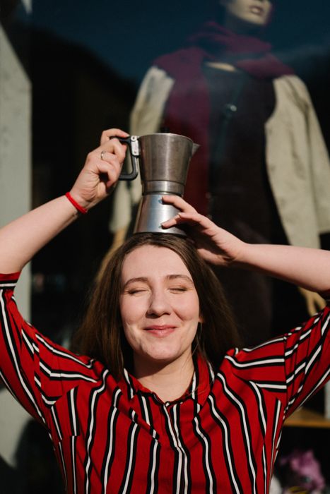Lilla balancing a moka pot on her head and smiling